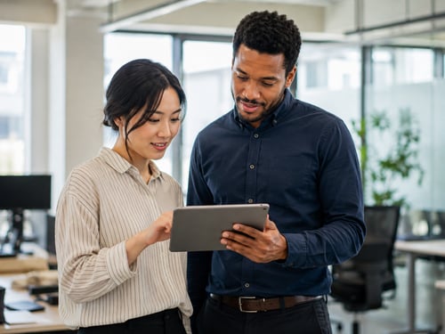 Two employees reviewing payroll and timekeeping information together on a tablet.